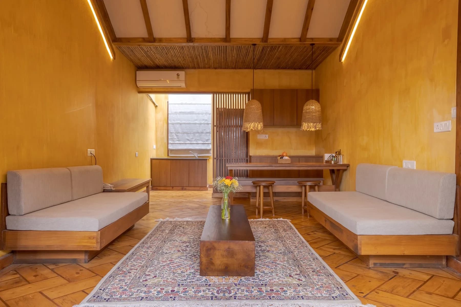 Kaansya villa lounge with twin sofas, parquet floor and traditional rug under a vaulted timber ceiling